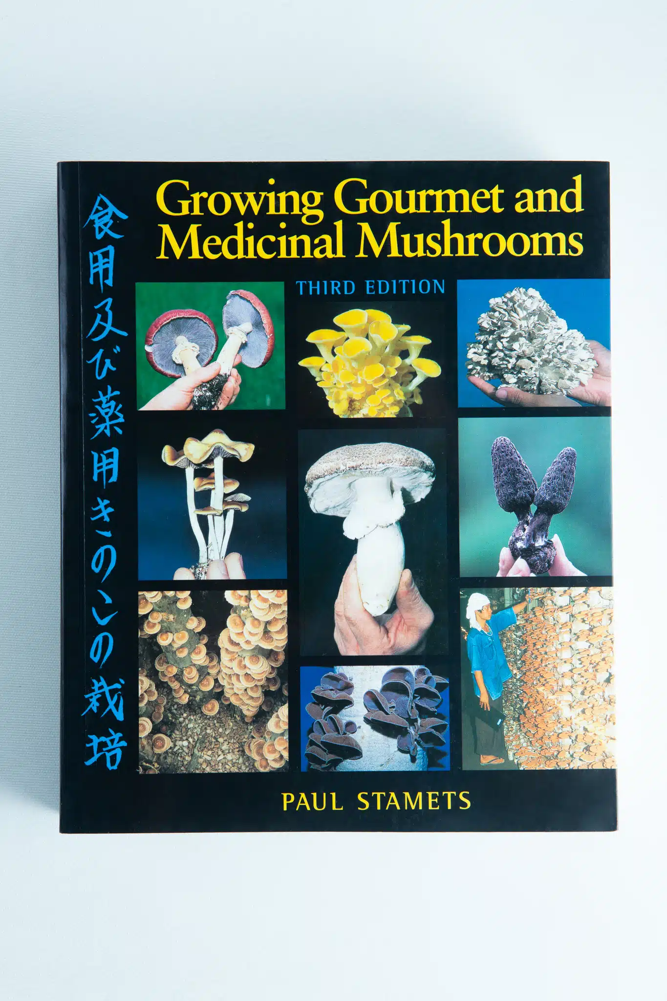 The cover of Growing Gourmet and Medicinal Mushrooms: Book By Paul Stamets features colourful mushroom photos with the title shown in English and Japanese.