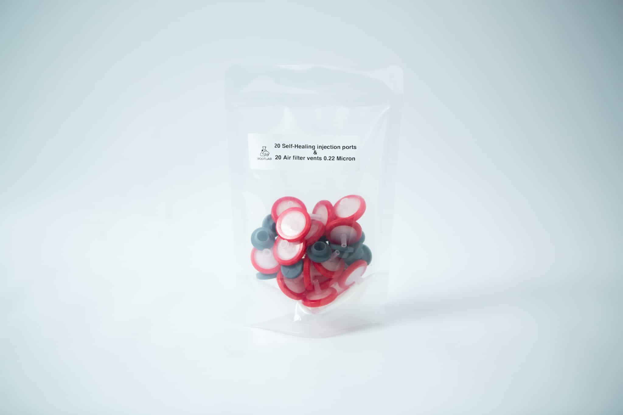 Rubber Self Healing Injection port and Syringe Filter PTFE for Mycology 1 A clear plastic bag of Rubber Self-Healing Injection port and Syringe Filter PTFE for Mycology, with product details labelled on the front. The upright bag contains red, white ports, and grey syringe filters against a white background.