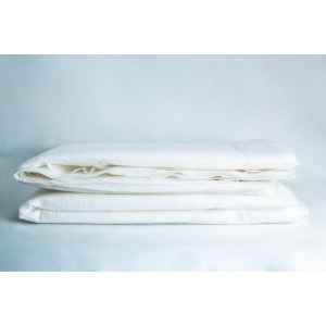 A stack of two folded white Log Blankets sits on a white surface against a light background.