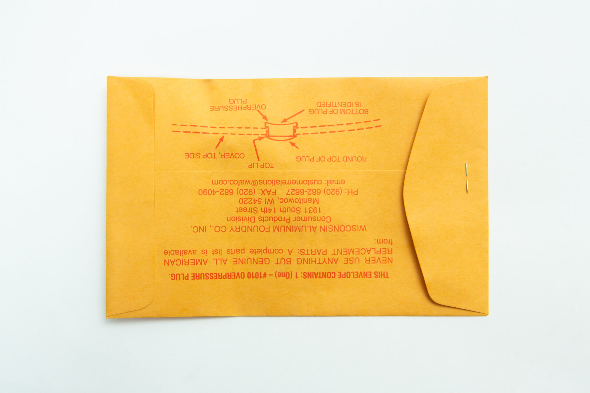 All American rubber overpressure plug for sterilizer | Orange | Part 1010 3 A sealed yellow envelope with two metal fasteners lies on a white surface. Red text on the back shows instructions and manufacturer details for the All American rubber overpressure plug for steriliser | Orange | Part 1010.