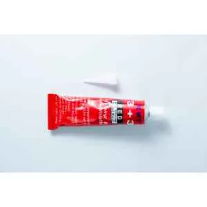 A red tube labelled "High Temperature RTV Silicon-Red" with a white cap placed above it lies on a white surface. The tube displays black and white text and likely contains high temperature red RTV silicone adhesive.