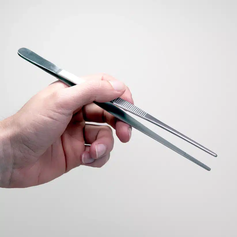 Plant Cell Tissue Culture Starter Kit 10 A hand holds metal tweezers—part of the Plant Cell Tissue Culture Starter Kit—for handling delicate samples, shown against a plain light background.