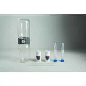 The Plantcell Synthetic Seed Starter Kit includes a clear plastic bottle with a grey connector, two small white containers with purple Plantcell labels, two capped test tubes containing white material, and a clear dropper arranged on a grey surface.