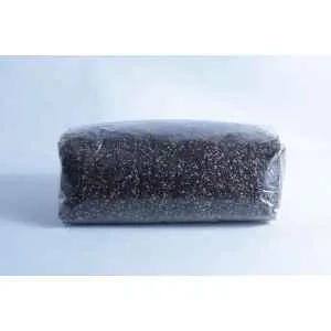 Home 16 A 2KG block of CVG Monotub Mushroom Bulk Substrate (Coco, Verm, Gypsum), dark and granular, tightly wrapped in clear plastic and placed on a plain light-coloured surface with a neutral background.