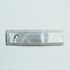 Home 10 A rectangular piece of silver metal with a textured border and a small circular hole near one end, placed on a plain light background.