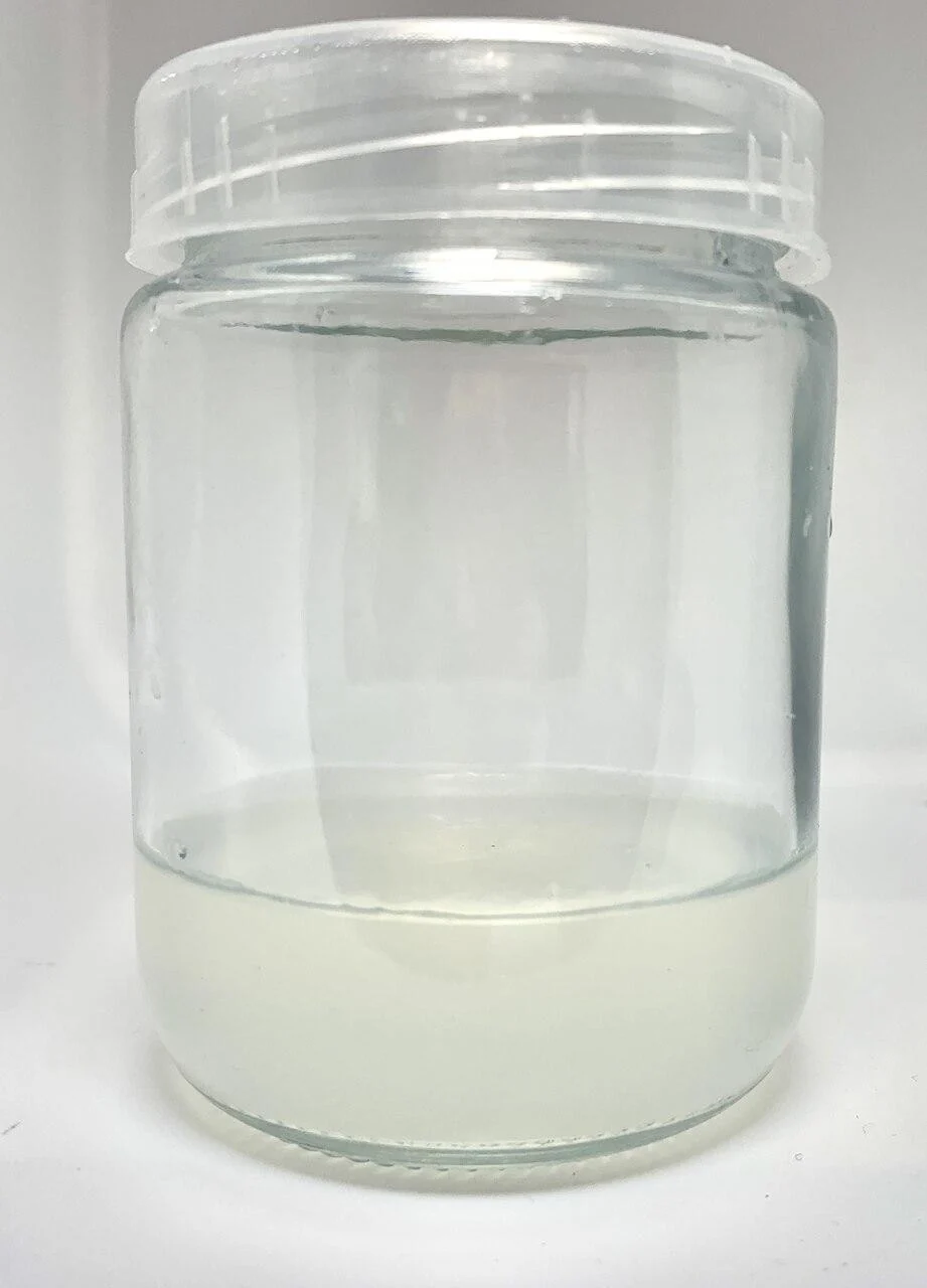Plant cell Gesolgel-MTC-Gellan gum( Low Acyl) 100g 4 A clear plastic jar with a white screw-on lid, centred against a plain white background, contains a small amount of cloudy, light-coloured liquid at the bottom. The label reads “Plant cell Gesolgel-MTC-Gellan gum (Low Acyl) 100g.”.