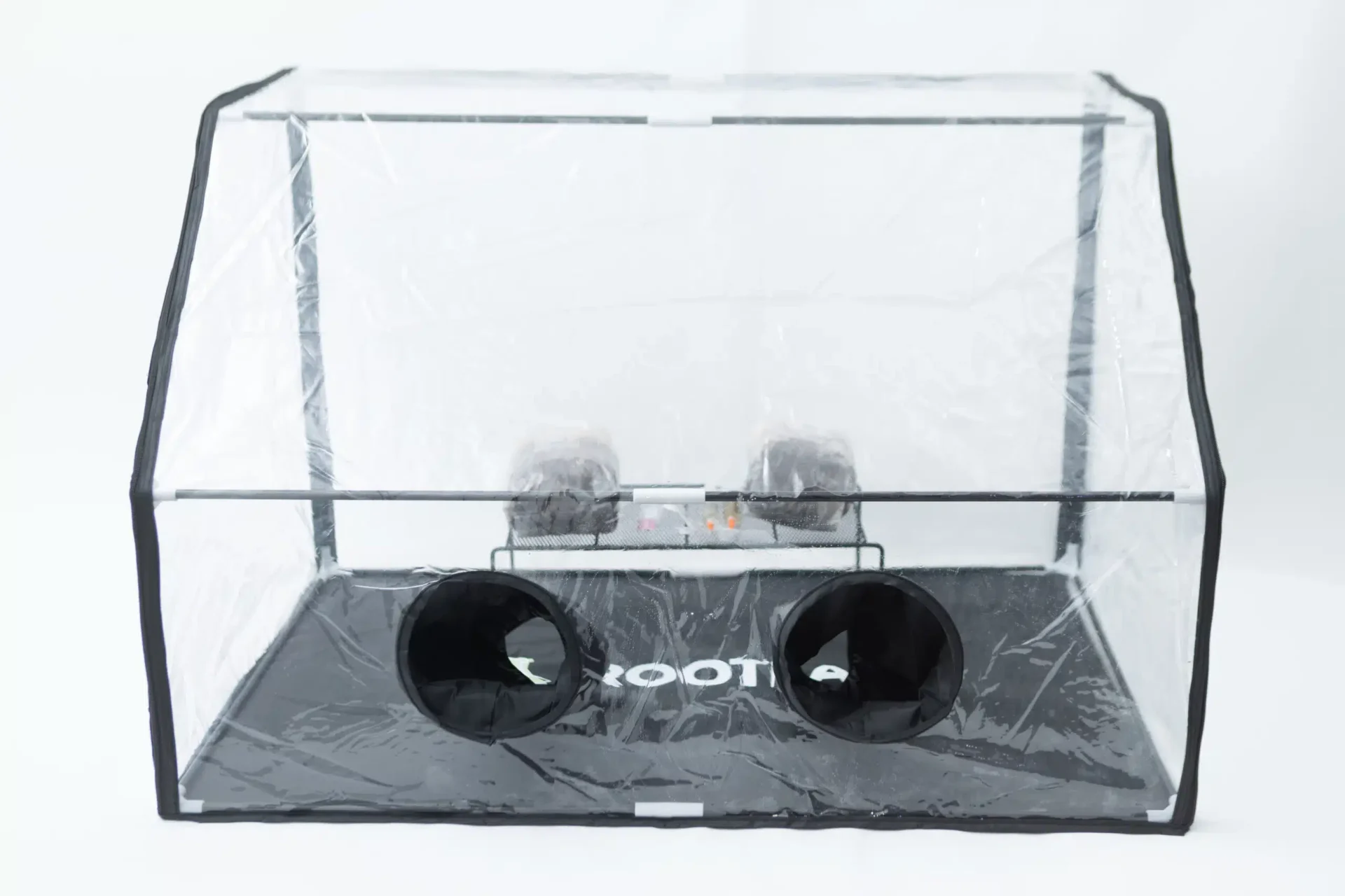 Rootlab Still Air Box with angled viewing window- XL 3 A rectangular clear plastic greenhouse with black trim and two round openings on the front panel, placed on a black mat labelled ROOT! inside the enclosure.